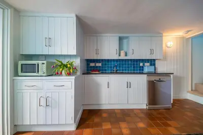 a kitchen with white cabinets and a microwave at Marine Cottage in Aldeburgh