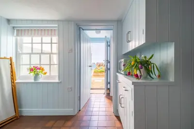 a kitchen with white cabinets and a window at Marine Cottage in Aldeburgh