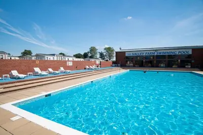 a large swimming pool with chairs and a building at Getaway House in Clacton-on-Sea