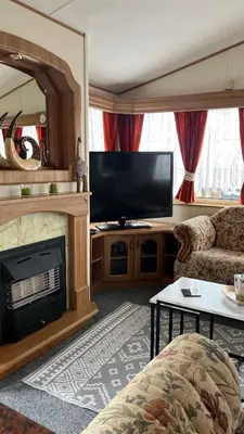a living room with a fireplace and a television at Caravan home Clacton-On-Sea St Osyth in Saint Osyth
