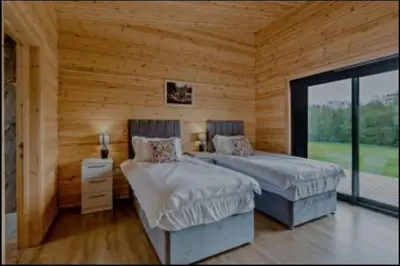 two beds in a room with wooden walls at Meadow Valley Lodge 4 in Ipswich