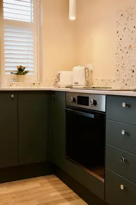 a kitchen with green cabinets and a black dishwasher at The Sunset Nook in Ipswich