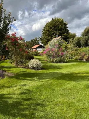 a garden with green grass and flowers and a house at The Sunset Nook in Ipswich