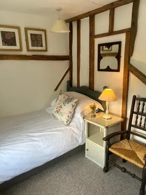 a bedroom with a bed with a lamp and a chair at Rose Cottage Darsham - Suffolk Coastal in Darsham