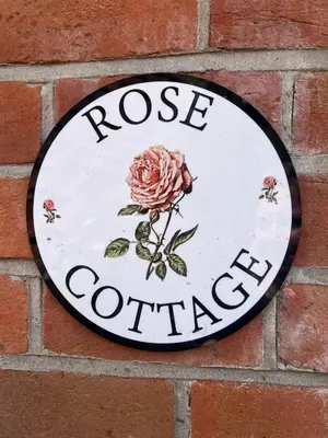 a clock on a brick wall with a rose garden on it at Rose Cottage Darsham - Suffolk Coastal in Darsham