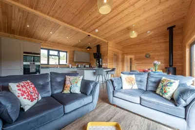 a living room with two blue couches and a kitchen at Meadow Valley Lodge 1 in Ipswich