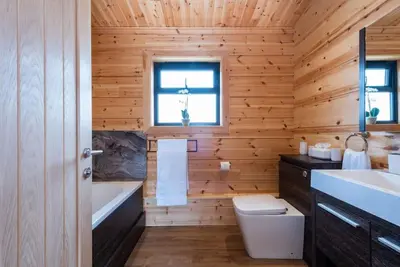 a wooden bathroom with a tub and a toilet and a sink at Meadow Valley Lodge 1 in Ipswich
