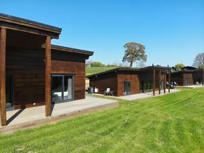 a log cabin with a grass field next to it at Meadow Valley Lodge 1 in Ipswich