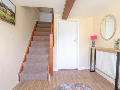 a staircase in a home with a mirror and a door at 3 The Almshouse in Saxmundham