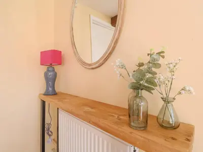 a mirror and two vases on a dresser with flowers at 3 The Almshouse in Saxmundham