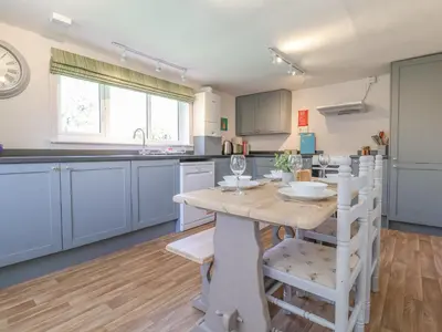 a kitchen with blue cabinets and a wooden table and chairs at 3 The Almshouse in Saxmundham