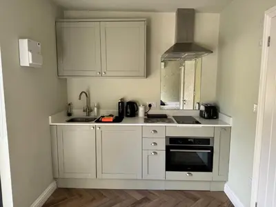 a kitchen with white cabinets and a sink and a stove at Gorgeous studio! in Cherry Hinton