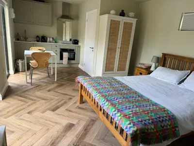 a bedroom with a bed and a kitchen with a table at Gorgeous studio! in Cherry Hinton