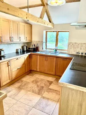 a large kitchen with wooden cabinets and a sink at Oak Grange holiday cottage in Hoxne