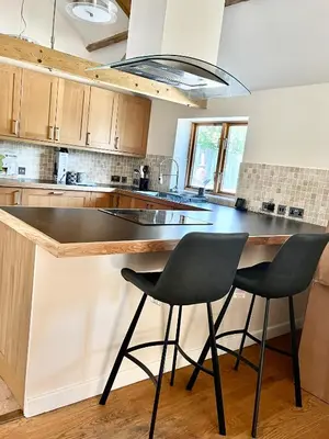 a kitchen with two black chairs at a counter at Oak Grange holiday cottage in Hoxne