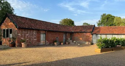 a brick house with potted plants in front of it at Oak Grange holiday cottage in Hoxne
