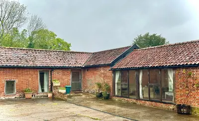 a red brick house with a large window at Oak Grange holiday cottage in Hoxne