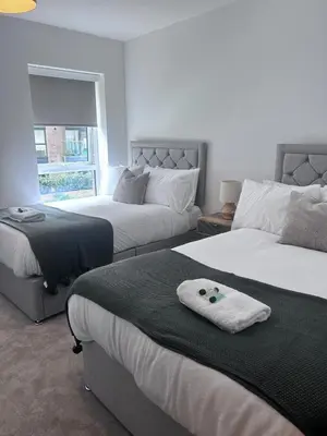 a bedroom with two beds and a couch and a window at The Ivy Abode 2 bedroom Apartment in Harlow
