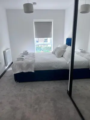 a bedroom with a large bed and a mirror at The Ivy Abode 2 bedroom Apartment in Harlow