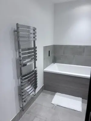 a bathroom with a white tub and a white towel at The Ivy Abode 2 bedroom Apartment in Harlow