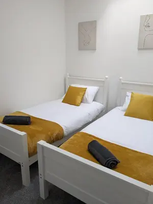 two beds in a room with white walls and yellow pillows at Cosy Central Home, Sleeps 5 by Homes by Jacq in Colchester
