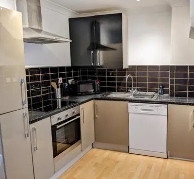a kitchen with white appliances and black tiles on the wall at Cosy Central Home, Sleeps 5 by Homes by Jacq in Colchester