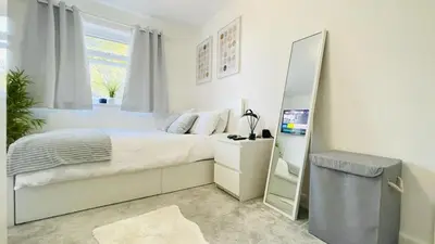 a bedroom with a large bed and a mirror at Lovely 3 bedroom house near city centre - Basildon in Basildon