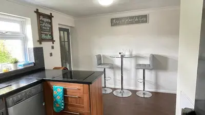 a kitchen with a counter and two stools at Lovely 3 bedroom house near city centre - Basildon in Basildon