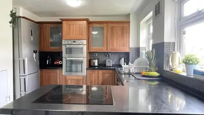 a kitchen with wooden cabinets and stainless steel appliances at Lovely 3 bedroom house near city centre - Basildon in Basildon