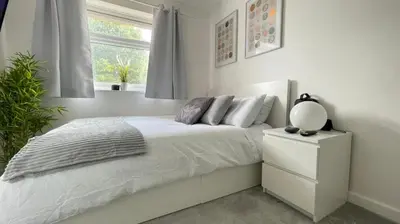 a white bedroom with a bed and a window at Lovely 3 bedroom house near city centre - Basildon in Basildon