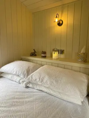 a bed with a white comforter in a room at Willow Shepherd Hut in West Row