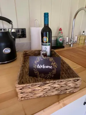 a bottle of wine in a basket on a counter at Willow Shepherd Hut in West Row