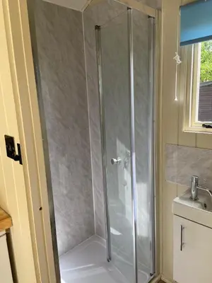 a shower with a glass door in a bathroom at Willow Shepherd Hut in West Row