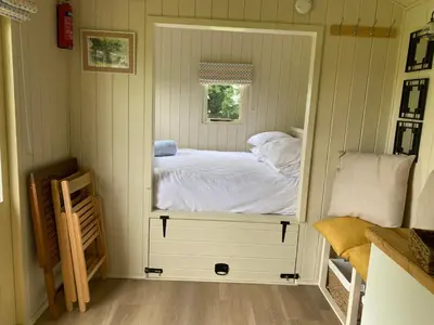 a small bedroom with a bed in a window at Willow Shepherd Hut in West Row