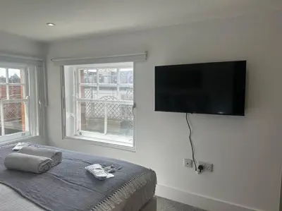 a bedroom with a bed and a flat screen tv on the wall at Relaxing 1 bedroom garden flat. in Brentwood