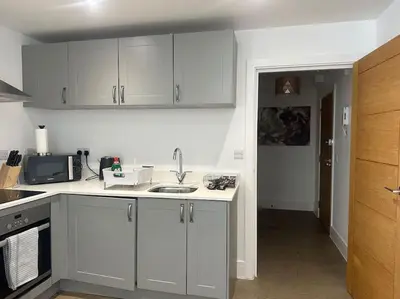 a kitchen with white cabinets and a sink at Relaxing 1 bedroom garden flat. in Brentwood