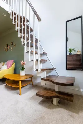 a living room with a staircase and a table at En-suite with double bed on mezzanine and desk in family home in Hertford