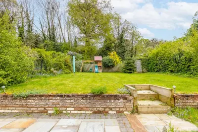 a garden with a retaining wall and stairs at En-suite with double bed on mezzanine and desk in family home in Hertford
