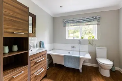 a bathroom with a tub and a toilet and a window at En-suite with double bed on mezzanine and desk in family home in Hertford