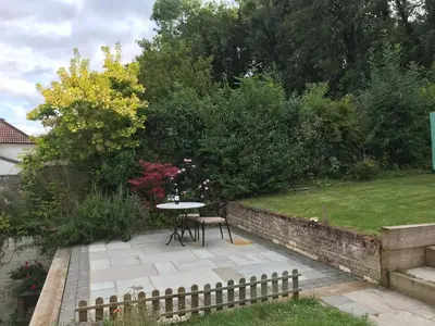 a patio with a table and chairs in a garden at En-suite with double bed on mezzanine and desk in family home in Hertford