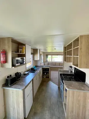 a large kitchen with wooden cabinets and counters at Caravan at Seawick Holiday Park Close to Beach in Saint Osyth