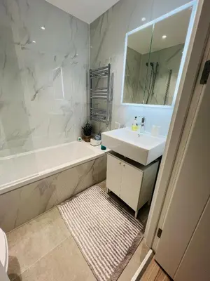 a bathroom with a sink and a tub and a mirror at Stunning New Penthouse Apartment in Southend-on-Sea