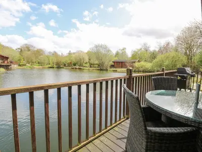 a balcony with a table and chairs and a river at Woodpecker Lodge in Langham