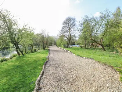 a gravel road in a park with trees and grass at Woodpecker Lodge in Langham
