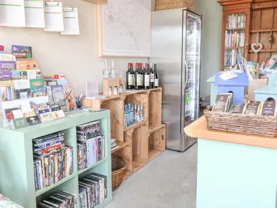 a store with a refrigerator and a shelf with books at Woodpecker Lodge in Langham