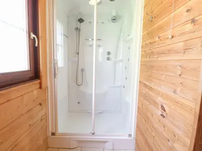 a shower with a glass door in a bathroom at Woodpecker Lodge in Langham
