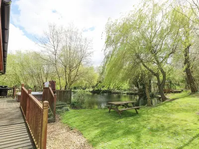 a park with a picnic table next to a river at Kingfisher Lodge in Langham