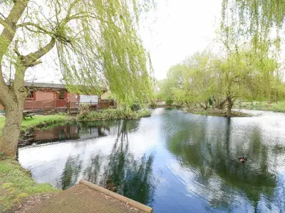 a view of a river with trees and a building at Kingfisher Lodge in Langham