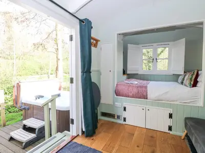 a small bedroom with a bed and a window at Damsel Shepherds Hut in Badwell Ash