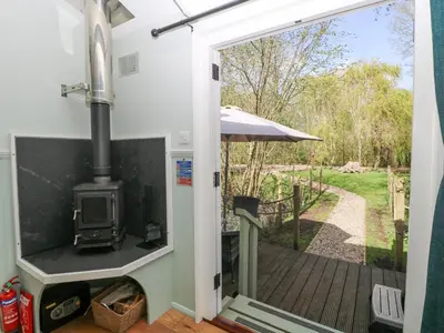 an open door to a patio with an outdoor stove at Damsel Shepherds Hut in Badwell Ash